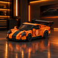 Orange Porsche 911 style LEGO model with black wing in a dark premium garage with orange ambient glow